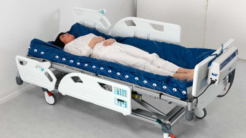ArjoHuntleigh-Products-Therapeutic-Surfaces-Acute-Care-Active-Therapy-Range-Nimbus-Professional-Deflated-Mattress-on-Enterprise-Bed-Female-Patient_Product_Page_Main_Image.jpg